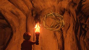 cropped view of a lego character holding a lit torch looking up at knotwood growing from a cave wall